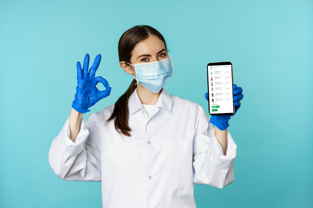 portrait-of-doctor-in-medical-face-mask-and-gloves-showing-mobile-phone-app-smartphone-screen-and-ok.jpg portrait-of-doctor-in-medical-face-mask-and-gloves-showing-mobile-phone-app-smartphone-screen-and-ok.jpg